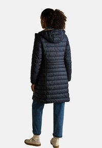 Musthave muströga mustkunstvest, millel on kapuuts ja vertikaalne õmblus. Kanda siniste teksade ja kreemivärvi kingadega, näidates juhuslikku, kaasaegset siluetti.