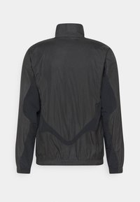 Zwarte jas met een gestructureerd ruitpatroon, hoge kraag en contrasterende zwarte accenten. Heeft een gestructureerd ontwerp en elastische manchetten.