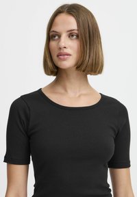 Top nero a coste con scollatura rotonda e maniche corte, caratterizzato da un design aderente e una texture liscia.