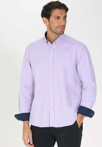 Chemise boutonnée violet clair à manches longues, avec des poignets bleu marine et une texture subtile. Comprend des boutons blancs et un col classique.