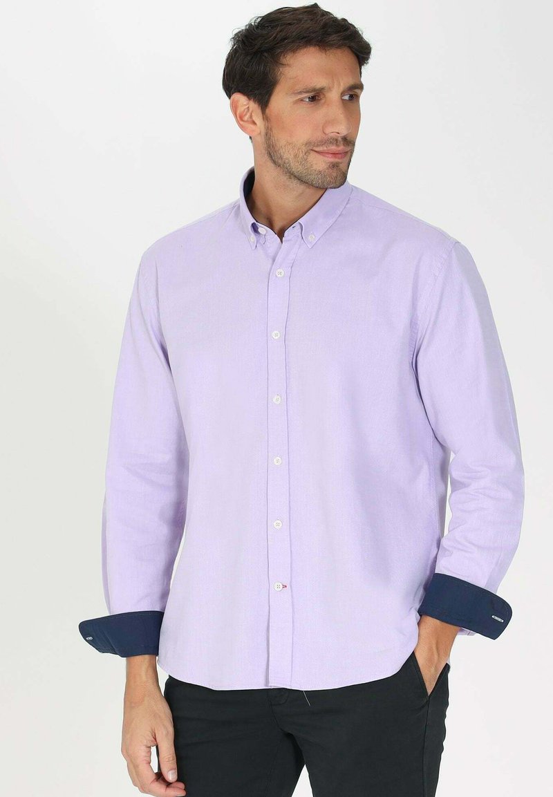 Chemise boutonnée violet clair à manches longues, avec des poignets bleu marine et une texture subtile. Comprend des boutons blancs et un col classique.