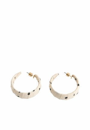 Ohrringe mit creméfarbenem Stoff bezogenem Bügel, schwarzen unregelmäßigen Punkten und goldfarbenen Metallsteckern und -verschlüssen.