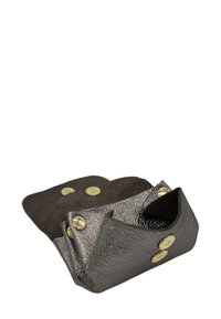 Petit plateau en cuir noir avec boutons-pression dorés, bords ouverts et pliés créant un contenant compact sur fond blanc.