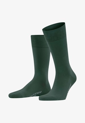 Grüne Socken aus weichem Material mit einem gerippten Bündchen für zusätzlichen Komfort. Mittlere Wadenlänge mit glatter Textur und minimaler Markenkennzeichnung.