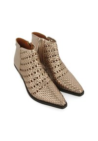 Botas de tobillo metálicas doradas con diseño trenzado, punteras puntiagudas y cremalleras laterales. La parte superior lisa contrasta con el material trenzado texturizado.