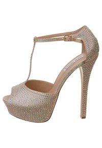 Chaussure à talon haut beige avec un bout ouvert, ornée de clous irisés, dotée d'une bride T et d'une fermeture à boucle, avec une semelle à plateforme.