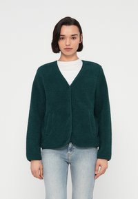 Τζάκετ από περκάλι σε τιρκουάζ χρώμα με μαλακή, υφασμάτινη επιφάνεια, ανοιχτό μπροστινό μέρος και δύο πλαϊνές τσέπες. Διαθέτει χαλαρή εφαρμογή και μακριά μανίκια.