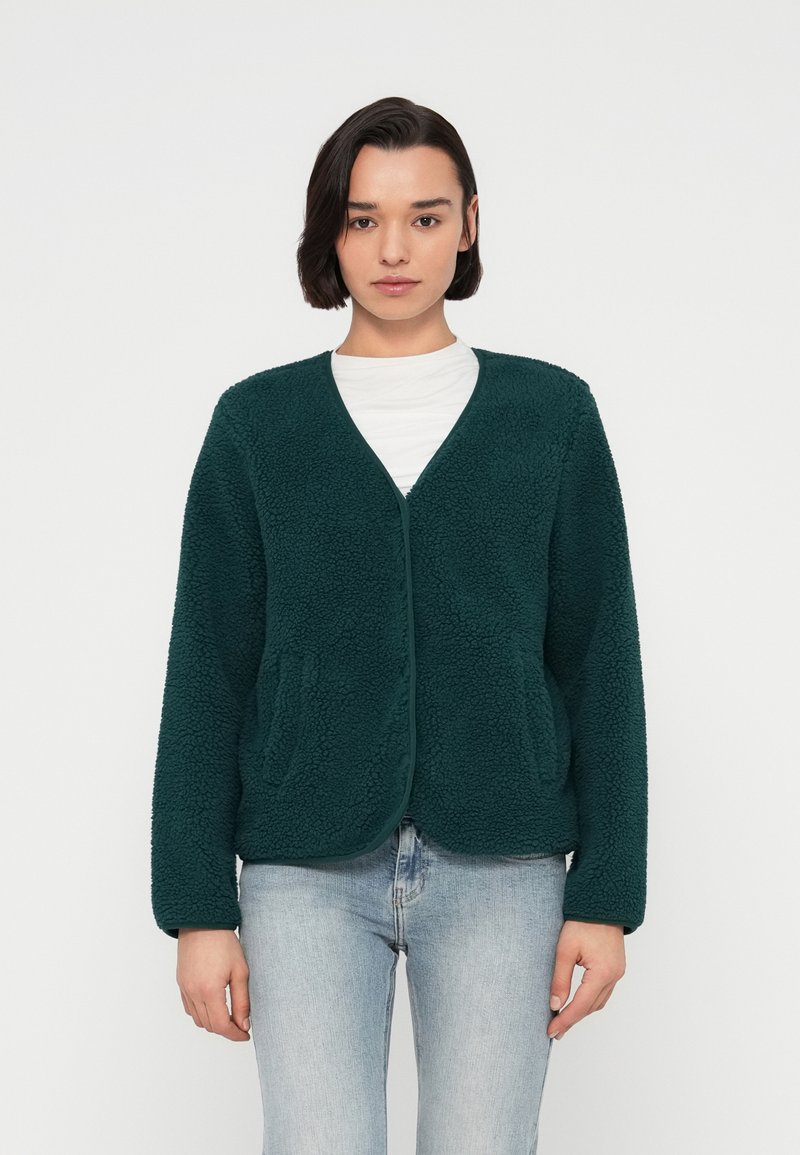 Τζάκετ από περκάλι σε τιρκουάζ χρώμα με μαλακή, υφασμάτινη επιφάνεια, ανοιχτό μπροστινό μέρος και δύο πλαϊνές τσέπες. Διαθέτει χαλαρή εφαρμογή και μακριά μανίκια.