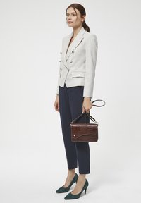 Jasnoszara marynarka podwójnie zapięta, granatowe spodnie, turgielowe czółenka na szpilkach oraz ciemnobrązowa torebka ze wzorem krokodylej skóry i krótkim uchwytem.