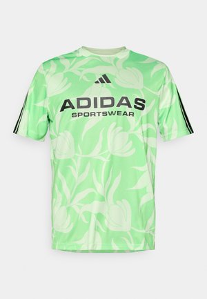 Camicetta verde chiaro a maniche corte con motivo floreale, con logo nero "ADIDAS" e testo "SPORTSWEAR". Strisce nere sulle maniche.