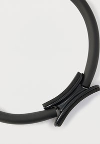 Μαύρος κυκλικός λαστιχένιος δακτύλιος με υφή στην επιφάνεια, συνδεδεμένος με έναν λείο μαύρο πλαστικό σύνδεσμο, με μινιμαλιστικό σχέδιο.