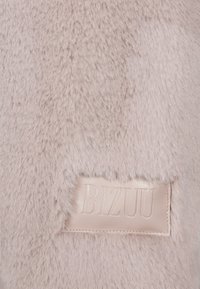 Nepbont stof in lichtroze, met een gestructureerd oppervlak en een gestikt beige leren label met de opdruk "BIZUU."