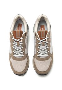 Zapatillas beige y grises con material de malla y ante. Presentan cordones blancos, detalles en cuero marrón y una suela de goma negra.