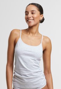 Lichtgrijze camisoletop met dunne bandjes, gemaakt van zachte, rekbare stof. Heeft een aansluitend ontwerp en een lichte ruching aan de zijkanten. Lichtgewicht en casual.