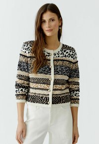Strickjacke mit Leoparden- und Tribal-Mustern in Schwarz, Creme und Beige, mit rundem Halsausschnitt und Knopfverschluss. Strukturierter Stoff.