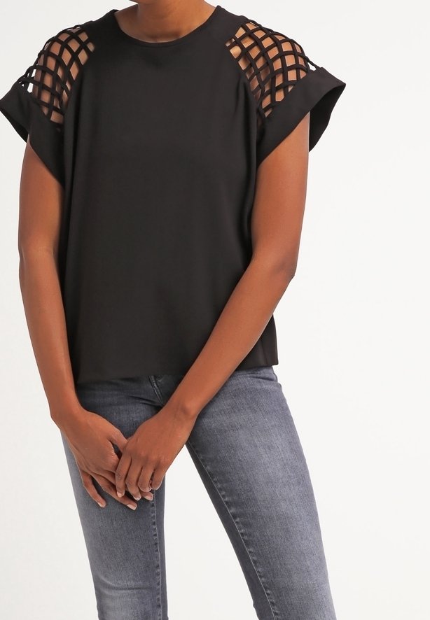Top nero a maniche corte con design a rombi sulle spalle. Tessuto morbido, vestibilità comoda, abbinato a jeans grigi.