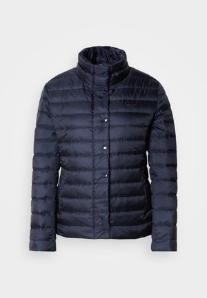 Giubbotto imbottito blu navy con colletto alto, motivo trapuntato orizzontale, chiusure a bottone e una superficie liscia e lucida. Adatto per il freddo.