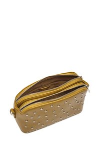 Żółta skórzana torba na ramię z metalowymi nitami, podwójnymi kieszeniami na zamek i gładką teksturą. Dodatki obejmują subtelne wykończenie wewnętrzne.