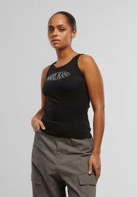 Débardeur noir à côtes avec un col rond et un détail de logo, associé à un pantalon cargo gris ample avec des poches latérales.
