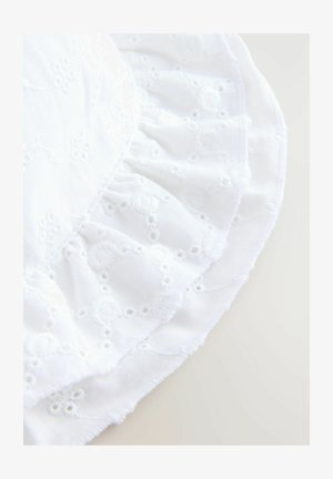 Weißer, bestickter Baumwollstoff mit einem gerafften Rüschensaum, der mit floralen Mustern und kleinen Lochdetails verziert ist und ein strukturiertes Erscheinungsbild erzeugt.