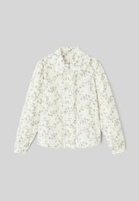 Blouse blanche à manches longues avec un motif floral gris. Col froncé et patte de boutonnage à l'avant avec des fermetures à bouton. Texture douce.