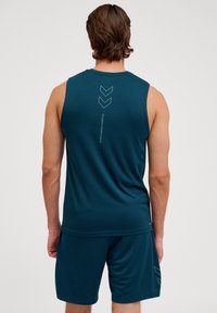 Donkerblauwe sporttanktop met een gladde textuur, gekenmerkt door een verticale logo en chevronontwerp op de achterkant. Draag met bijpassende shorts.