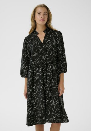 Zwarte jurk met witte stippen, met een V-hals, pofmouwen en een gathered taille. Gemaakt van lichte, gestructureerde stof.