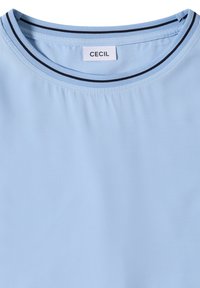 Chemise bleu clair avec encolure ronde ornée de rayures noires et blanches et une étiquette blanche cousue à l'intérieur indiquant "CECIL".