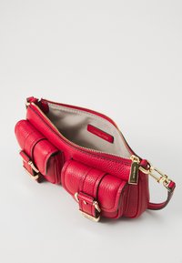 Red leather handbag with a textured finish, gold hardware, two front pockets with buckle accents, and a zip closure, interior in light fabric.