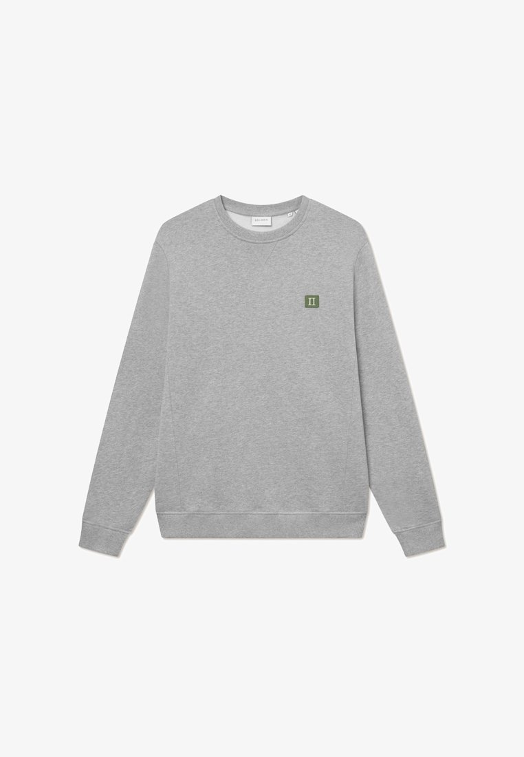 Sudadera gris hecha de una tela suave con cuello redondo, mangas largas, puños de canalé y un pequeño parche de logo verde en el pecho.