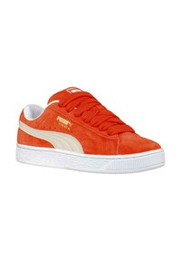 Sneakers in suede rosso con suola in gomma bianca, presentano lacci arancioni, striscia laterale beige e dettagli del logo in oro sul lato.