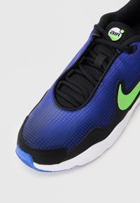 Kadar izbliza plave i crne Nike Air Max tenisice s zelenim swooshom i dizajnom vezanja, prikazujući teksturiranu gornjište i bijeli potplat.