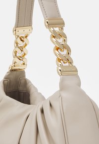 Beige leather handbag with pleated design and gold chain hardware. Features sturdy straps and a soft, textured surface.