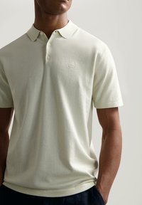 Lys grønn polo skjorte laget av myk stoff. Har en klassisk krage, tre knapper og subtilt brodert logo på brystet. Korte ermer.