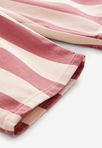 Tissu rayé bordeaux et écru avec une finition texturée, présentant des bords soigneusement cousus et un ourlet replié.