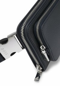 Svart texturerad läderplånbok med två silverdragkedjor och ett silverlås ingraverat med "BOSS".