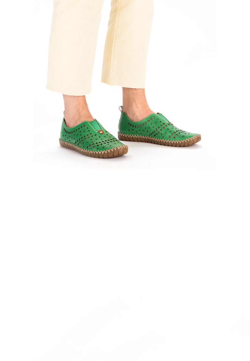 Baskets vertes à enfiler avec des découpages, semelle en caoutchouc et coutures beige. Elles disposent d'un onglet à l'arrière pour un enfilage facile.