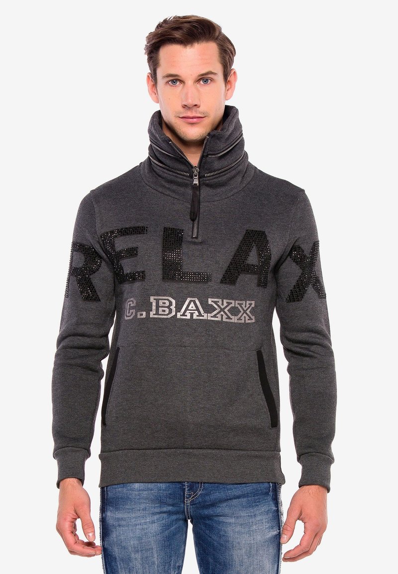Grauer Sweatshirt mit hohem Kragen, ausgestattet mit einem Frontreißverschluss, "RELAX" aus schwarzen Pailletten und seitlichen Taschen. Weiches Material mit subtiler Textur.