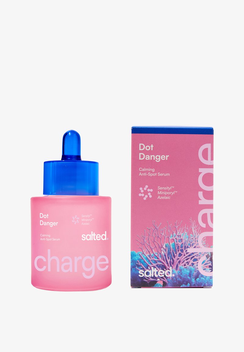 Flacon compte-gouttes rose et boîte assortie du sérum apaisant anti-imperfections Dot Danger de Salted avec un bouchon bleu et un motif corail sur la boîte.