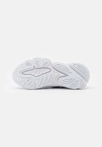 Shoe sole with a textured, white rubber design. It features wave patterns and a central groove for flexibility and traction.
