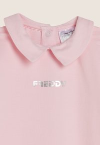 Camicia di cotone rosa con colletto, con un logo metallico argento "FREDDY" sul davanti. Chiusura a bottone sul retro.