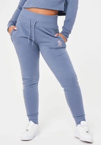 Ljusblåa sweatshirtbyxor med tapered passform, ribbad midja, dragsko och broderade accenter i roséguld. Slätt tyg i bomullsblandning.