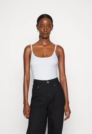 Light gray sleeveless bodysuit with a scoop neckline paired with high-waisted black jeans featuring a button closure and side pockets.
