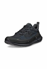 Svart idrottssko med meshöverdel, förstärkt tå och dämpad sula. Har texturerade detaljer och en dragflik för enkel påtagning.