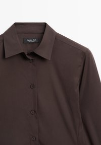 Bruine overhemd met knopen en een klassieke kraag, vervaardigd uit zachte stof, met een label op de kraag en vijf knopen aan de voorkant voor sluiting.