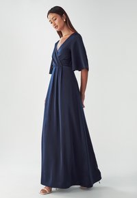 Navy blue, floor-length dress in smooth fabric with a V-neck, flutter sleeves, and a wrapped waist for a fitted silhouette.