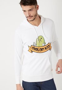 Sudadera blanca con capucha, que presenta un gráfico de una sandía sonriente y el texto "melon KID" en una banda naranja. Puños y dobladillo acanalados.