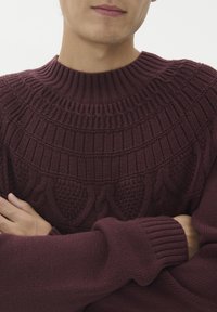 Bordeauxfarbener Strickpullover mit strukturiertem Einsatz und kreisförmigen sowie Kabelmustern; gerippter Kragen und Bündchen verbessern das Design und die Passform.