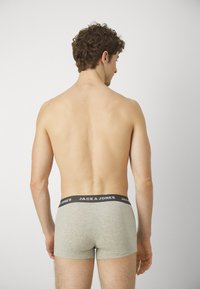 Graue Baumwoll-Boxershorts mit einem schwarzen Bund, der den Text "JACK & JONES" trägt, von hinten gezeigt und ein eng anliegendes Design enthüllend.