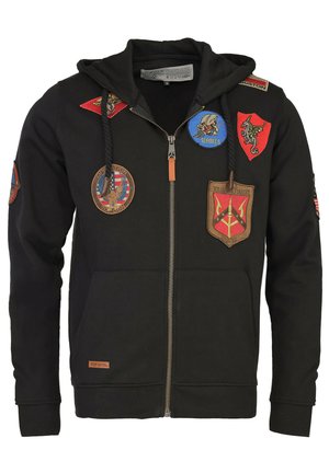 Schwarz zip-up Hoodie aus weichem Stoff, mit verschiedenen gestickten Patches in Farben wie Rot, Blau und Braun. Mit Kapuze und Kordelzug.